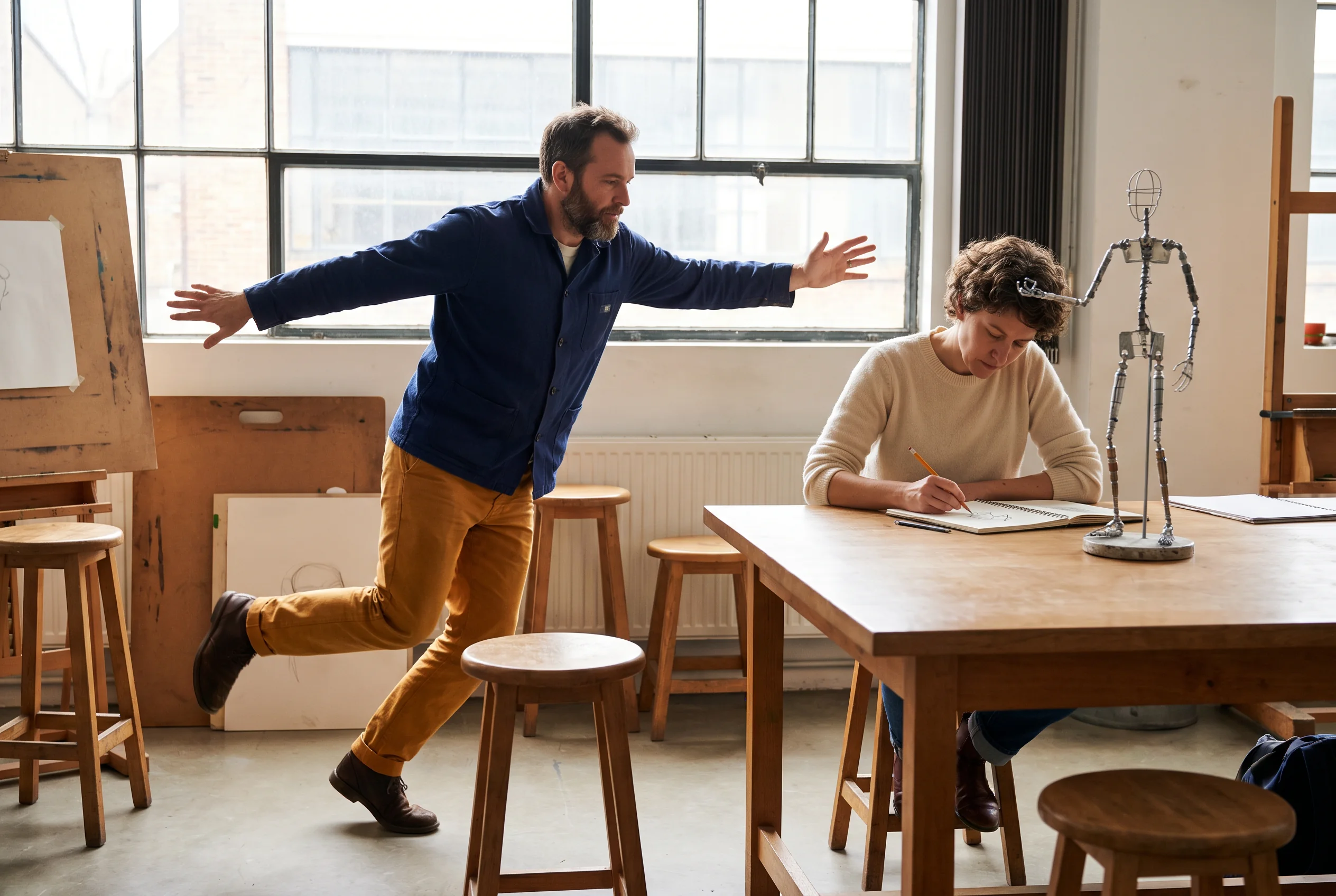 Animator using an expressive movement pose while another artist observes